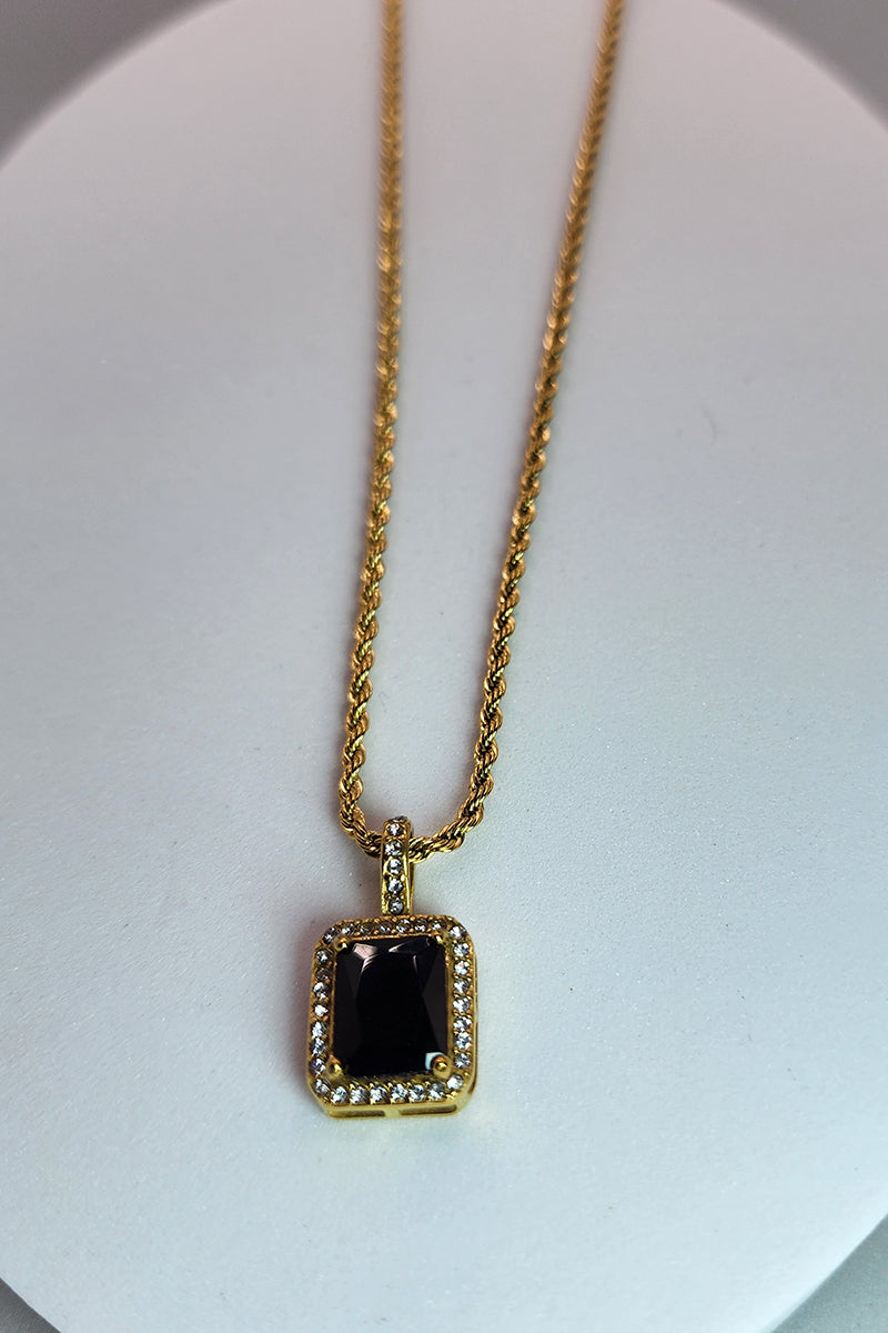 Gold necklace with a black pendant on a white background